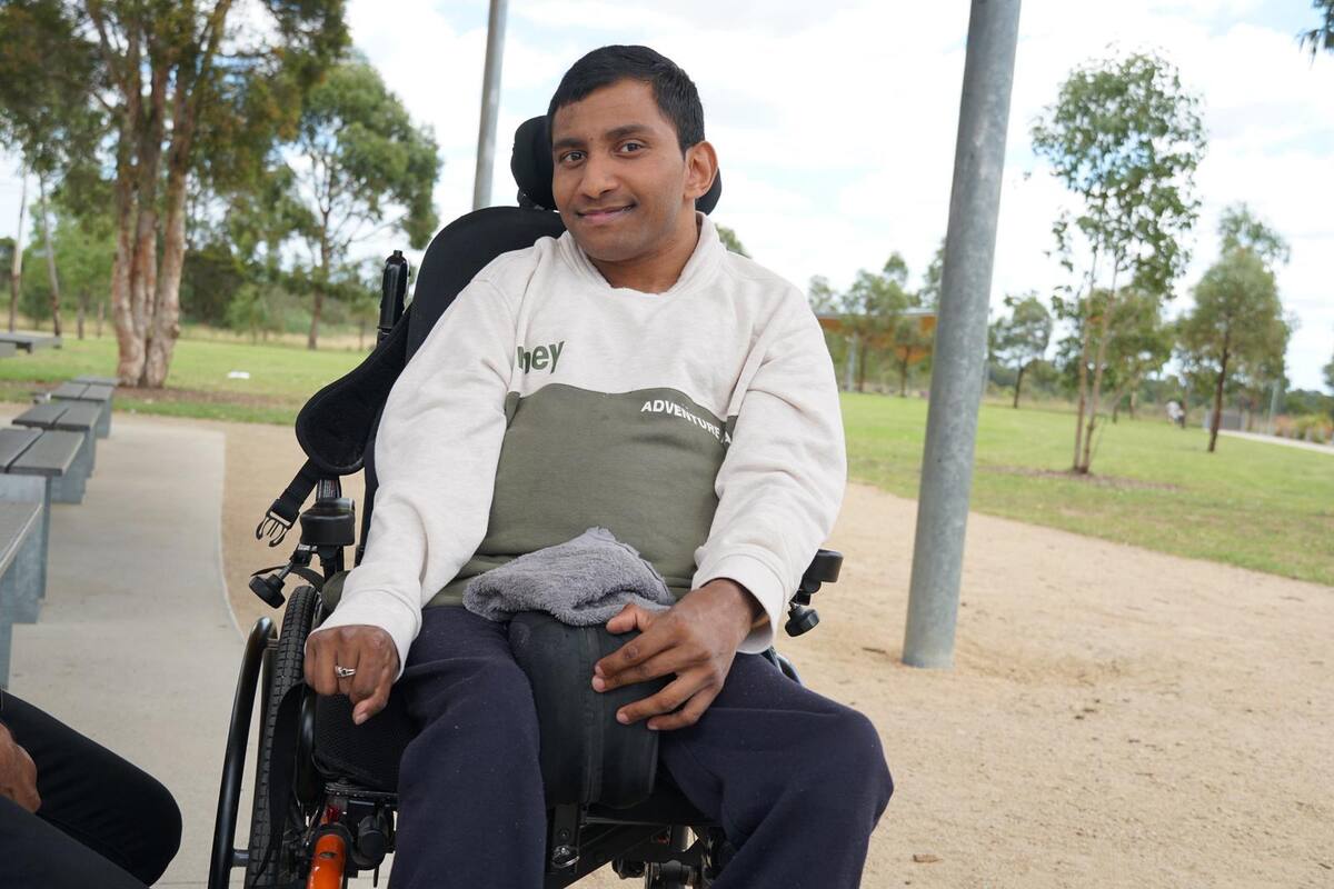 An Enable Hub participant smiling in his wheelchair at a local park
